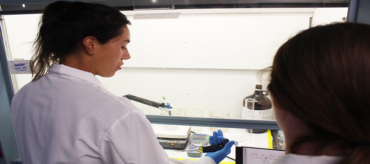 Lela Schlenker and Gabrielle Menard working together under the hood in the lab